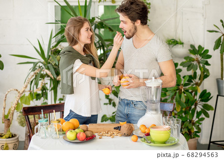 beautiful fair-haired girl giving an orange to her handsome bear 68294563