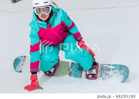 beautiful snowboarder is sitting on the snow 68295190