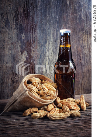 Peanuts and beer on wood background Peanuts and beer on wood background 68296879