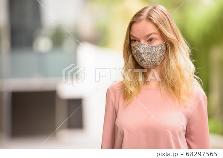 Young blonde woman with mask thinking in the city with nature Young blonde woman with mask thinking in the city with nature 68297565