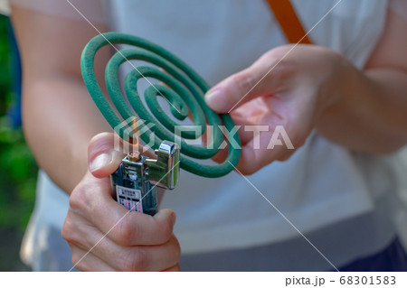 蚊取り線香を持った女性が、右手に持ったライターで着火している 蚊取り線香を持った女性が、右手に持ったライターで着火している 68301583