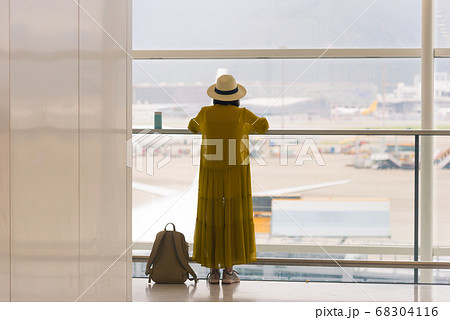 Back view of traveling girl standing near window at the international airport terminal Back view of traveling girl standing near window at the international airport terminal 68304116