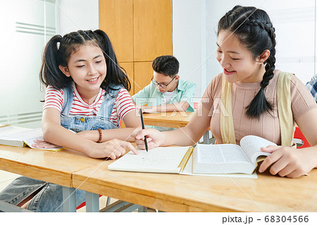 Girl helping classmate with project 68304566