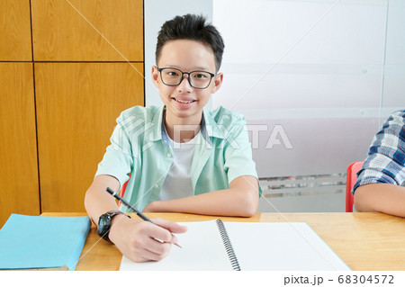Teenage boy writing in copybook Teenage boy writing in copybook 68304572