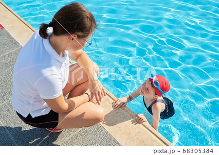 Sports girl child in outdoor pool talking with mother 68305384