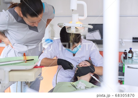 Experienced doctor dentist advising young intern of treating patient Experienced doctor dentist advising young intern of treating patient 68305870