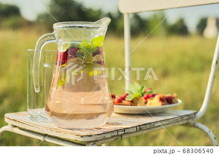 Cake with berries and jug with strawberry mint drink in summer sunny meadow 68306540