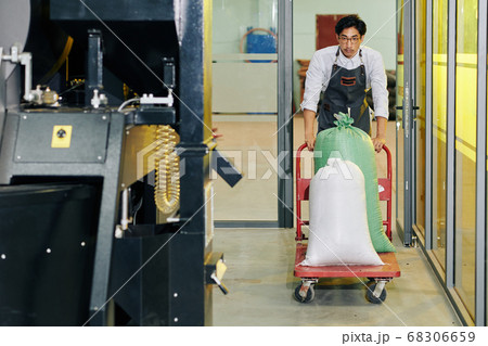 Roastery worker pushing cart with sacks 68306659