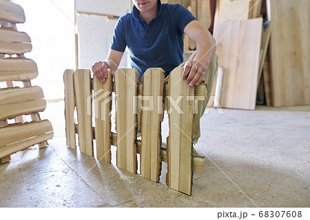 Male carpenter showing new made wooden low fence in carpentry 68307608