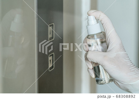 Closeup Asian woman hand wearing medical gloves and spraying Anti-Bacterial Sanitizer Spray to the elevator button before cleaning press, Coronavirus Network Outbreak, health care and cleaning covid19. 68308892
