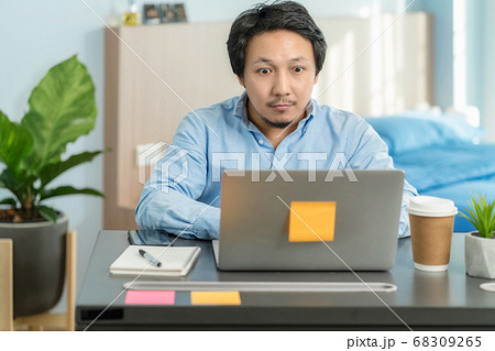 Asian business man using technology laptop and working from home with surprise action in bedroom of house by video conference call,startups and business owner,social distance and new normal concept 68309265