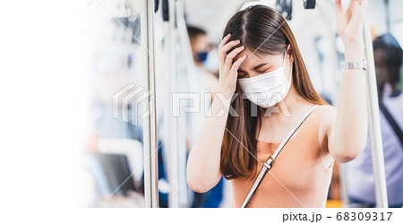 Young Asian woman passenger wearing surgical mask and Having a headache in subway train when traveling in big city at Covid19 outbreak, Infection and Pandemic,new normal and illness prevention concept 68309317