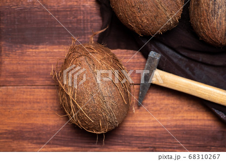 Open coconut and a small hammer on a wooden table Open coconut and a small hammer on a wooden table 68310267