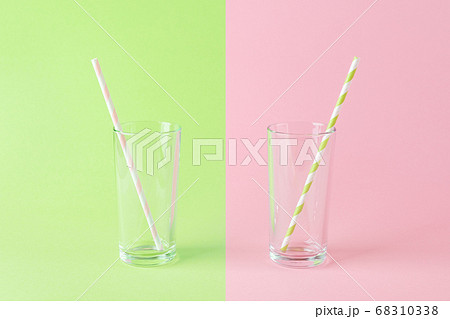 Two empty tall glasses with a paper drinking straws on a pink green background. 68310338