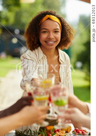 Smiling African Woman Clinking Glasses with Friends at Summer Party 68312013