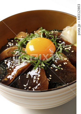 刻んだ海苔や大葉 ガリやワサビそして卵黄が中央に乗った鰹の漬け丼 白背景 の写真素材