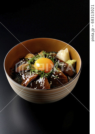 刻んだ海苔や大葉 ガリやワサビそして卵黄が中央に乗った鰹の漬け丼 黒背景 の写真素材