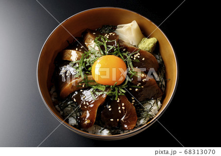 刻んだ海苔や大葉、ガリやワサビそして卵黄が中央に乗った鰹の漬け丼(黒背景、俯瞰) 68313070