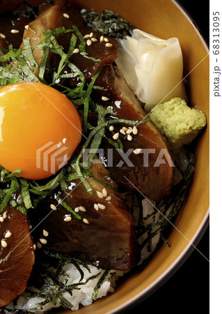 刻んだ海苔や大葉、ガリやワサビそして卵黄が中央に乗った鰹の漬け丼(黒背景、俯瞰) 68313095