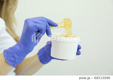 Young woman holding liquid yellow paste for 68313096