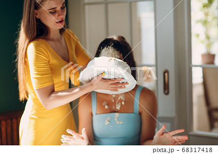 Young woman dips face in white cake with cream. Happy birthday concept. Young woman dips face in white cake with cream. Happy birthday concept. 68317418