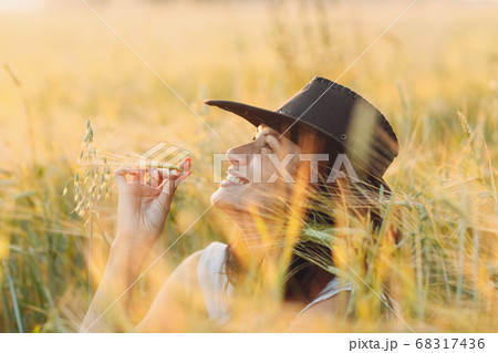 Woman farmer in cowboy hat at agricultural field on sunset 68317436