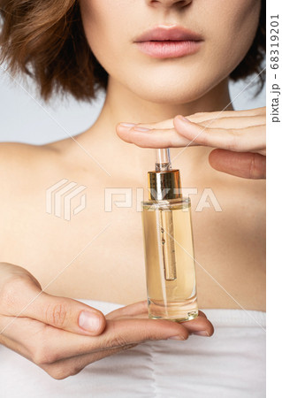 Young woman holding bottle of vitamin face serum Young woman holding bottle of vitamin face serum 68319201