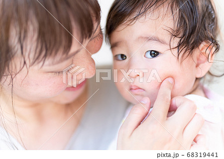 赤ちゃんのほっぺたをぷにぷにする若いお母さんの写真素材