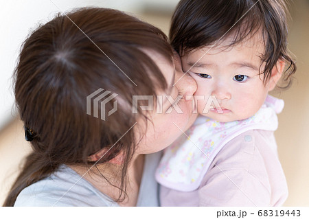 赤ちゃんのほっぺたにキスをする若いお母さんの写真素材