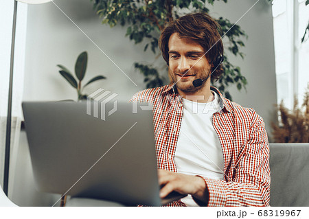 Young man wearing headset doing a video call by laptop 68319967