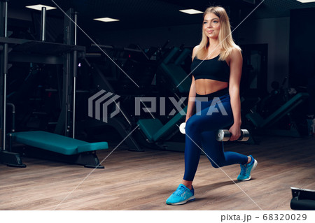 Curvy fit young blonde woman lifting dumbbell in a gym Curvy fit young blonde woman lifting dumbbell in a gym 68320029