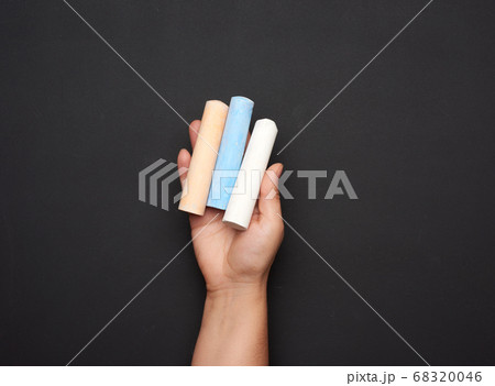 female hand holding three colored chalk on a female hand holding three colored chalk on a 68320046