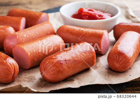 Juicy grilled half meat sausages with tomato sauce and ketchup on a wooden background. Fat fast food. Concept unhealthy eating. Juicy grilled half meat sausages with tomato sauce and ketchup on a wooden background. Fat fast food. Concept unhealthy eating. 68320644