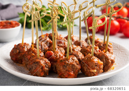 Beef meatballs stewed in tomato sauce on a plate on barbecue skewers. Light concrete background. 68320651