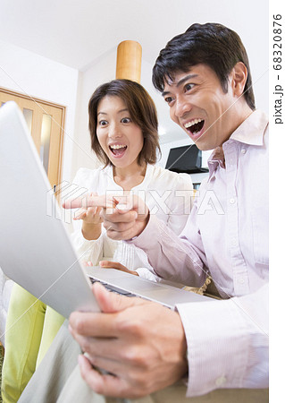 ノートパソコンを見るミドル夫婦 68320876