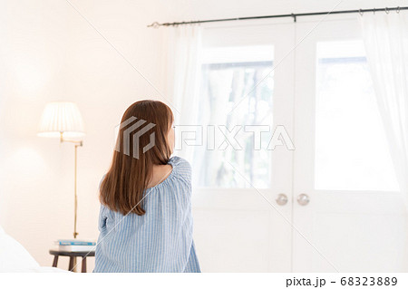 朝起きてベッドに座る若い女性の後ろ姿の写真素材 6238