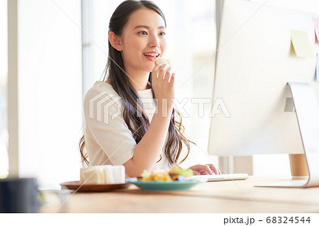 PCを見ながらランチを食べる女性 68324544