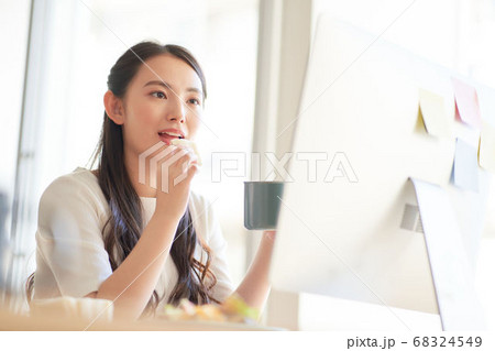 PCを見ながらランチを食べる女性 PCを見ながらランチを食べる女性 68324549