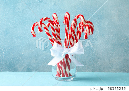 Candy canes in glass jar on blue background, space 68325256
