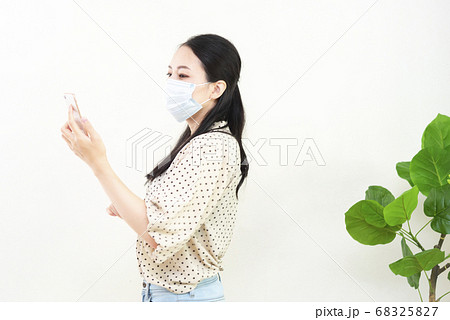 マスクをしてスマートフォンを持つ女性 マスクをしてスマートフォンを持つ女性 68325827