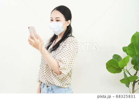 マスクをしてスマートフォンを持つ女性 マスクをしてスマートフォンを持つ女性 68325831