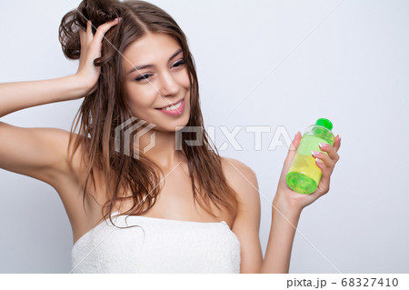 Young woman takes care of her hair using natural oils and conditioners for hair care Young woman takes care of her hair using natural oils and conditioners for hair care 68327410