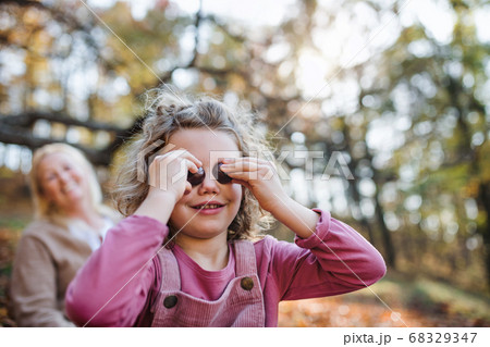 Small girl with grandmother on a walk in autumn forest, having fun. 68329347