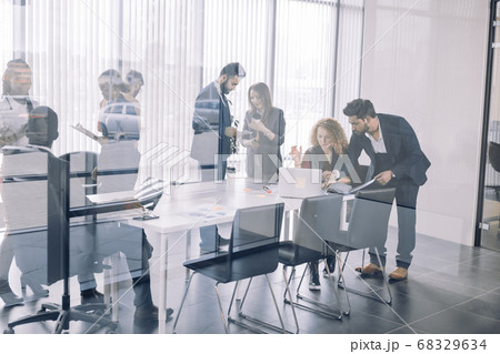 Diverse smiling businesspeople having conversation standing together at meeting. 68329634