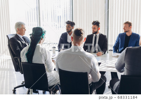 Multiracial male business executives discuss project sitting at conference table Multiracial male business executives discuss project sitting at conference table 68331184
