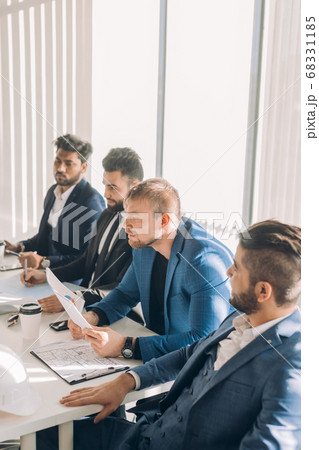 Multiracial male business executives discuss project sitting at conference table 68331185