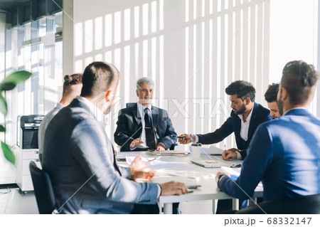 Multiracial male business executives discuss project sitting at conference table Multiracial male business executives discuss project sitting at conference table 68332147