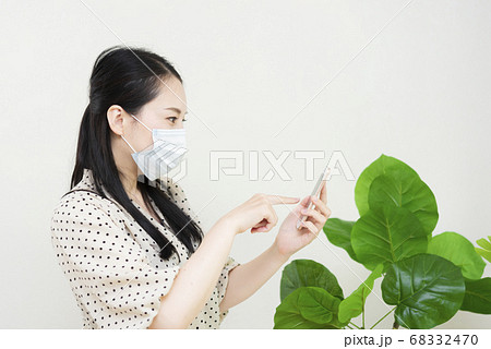 マスクをしてスマートフォンを操作する女性 68332470