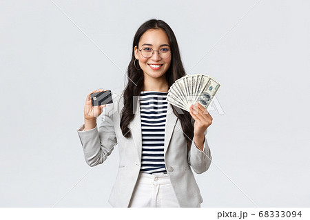 Business, finance and employment, entrepreneur and money concept. Successful asian businesswoman showing how increase income, hold credit card and money, smiling camera Business, finance and employment, entrepreneur and money concept. Successful asian businesswoman showing how increase income, hold credit card and money, smiling camera 68333094