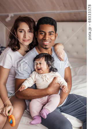 positive parents are smiling to camera while their little daughter is crying 68333378